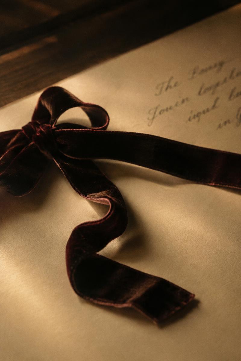 A velvet ribbon half undone on cream writing paper