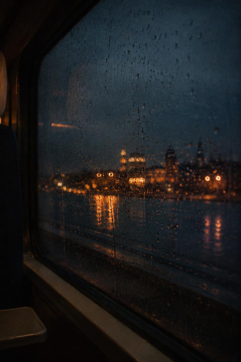 Rain running down a train window at night
